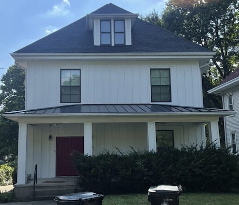 Two-story home with white board-and-batten siding and new roof
